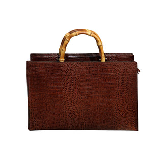 Brown textured handbag with a bamboo handle on a white background